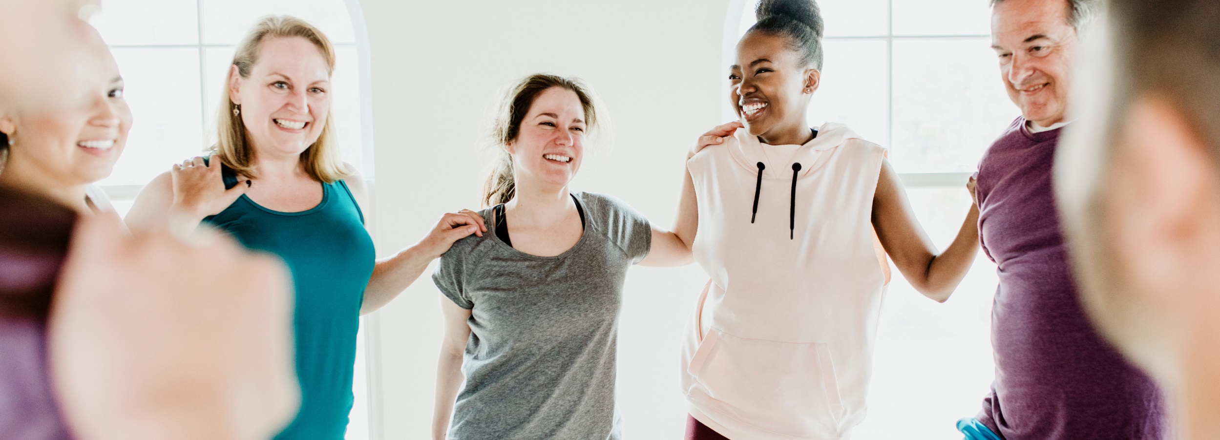 Eine vielfältige Gruppe von Menschen steht in einem hellen Raum im Kreis und gestikuliert fröhlich und unterstützend miteinander.

Auf dem Bild sind sechs Personen zu sehen, die in einem hellen, minimalistisch eingerichteten Raum stehen und einen Kreis bilden. Die meisten von ihnen sind Frauen unterschiedlichen Alters und unterschiedlicher ethnischer Herkunft, aber auch ein Mann mittleren Alters ist Teil der Gruppe. Alle lächeln und lachen herzlich, und ihre Körperhaltungen deuten auf eine positive und unterstützende Interaktion hin. Ihre Arme sind über die Schultern der anderen gelegt, was ein Gefühl von Gemeinschaft und Verbundenheit vermittelt. Die Kleidung, die sie tragen, ist sportlich und lässig, was darauf hindeutet, dass sie sich vielleicht zu einem Yoga-, Fitness- oder Meditationskurs versammelt haben oder gerade eine solche Aktivität beendet haben. Im Hintergrund ist ein großes Fenster zu sehen, durch das helles Tageslicht einfällt und die Atmosphäre des Bildes erhellt und freundlich macht. Die gesamte Stimmung des Bildes ist eine von Freude, Positivität, Zusammengehörigkeit und gegenseitiger Unterstützung in einer gesunden und aktiven Gemeinschaft.